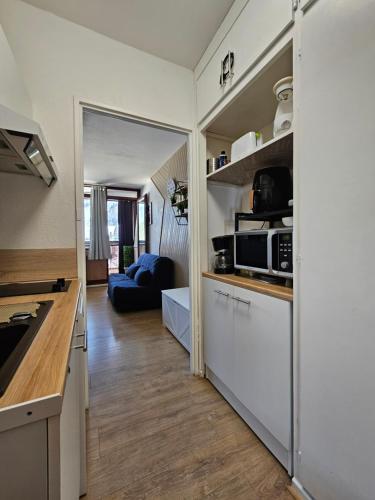 une cuisine avec des armoires blanches et un salon dans l'établissement Appartement proche lac de longemer, à La Bresse