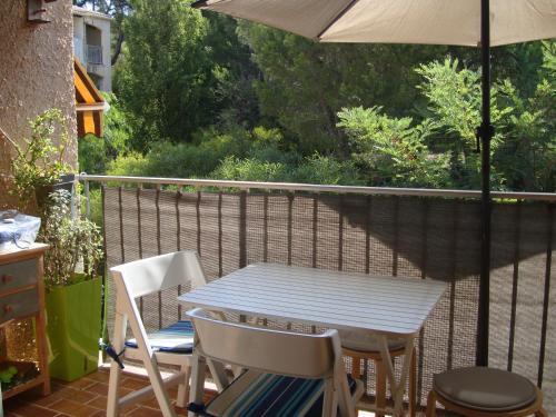 une table et des chaises sur un balcon avec un parasol dans l'établissement Studio bord de mer, aux Lecques