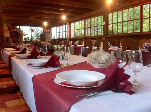 Tradicije Cigoc في Čigoč: طاولة مع الأطباق البيضاء والمناديل الحمراء وكؤوس النبيذ