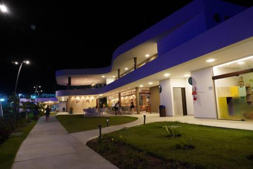 een gebouw 's nachts met een persoon die ervoor loopt bij Makia Beach Experience in Porto De Galinhas