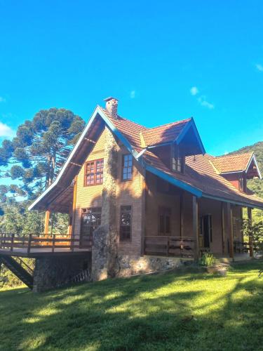 a house with a roof on a grass field at Chalé Coimbra in São Bento do Sapucaí