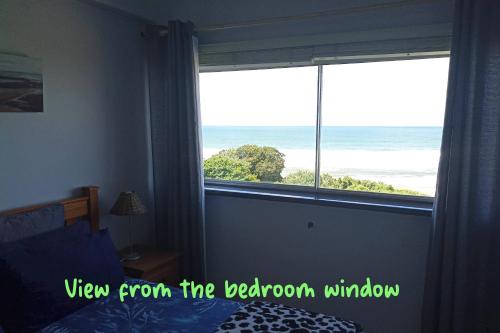a bedroom with a window with a view of the ocean at Driftsands 23 in Doonside