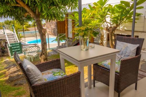 a table and chairs with a table and a pool at Residence Ma Vie Là Ltee in Le Morne