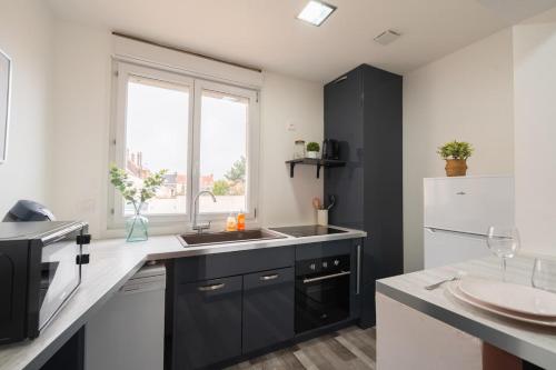 une cuisine avec un évier et un réfrigérateur blanc dans l'établissement Appartement 2 chambres pour 4 à 6 personnes Calais, à Calais