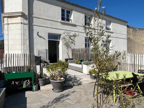 une maison blanche avec des plantes en pot devant elle dans l'établissement Très bel appartement avec grande terrasse 300m de la plage, à Royan