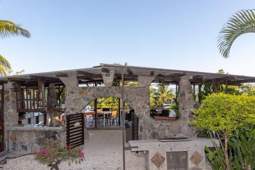 a stone house with a patio with a table at Residence Ma Vie Là Ltee in Le Morne
