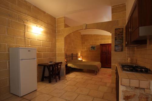 a kitchen with a refrigerator and a table with a bed at Residenza De Leonardis in Alberobello