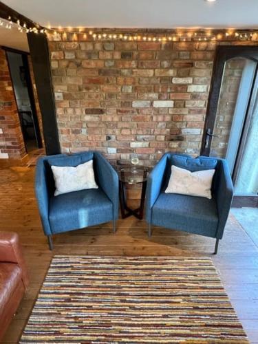 two blue chairs in a room with a brick wall at The Quintessential Dorset Cottage in Lytchett Matravers