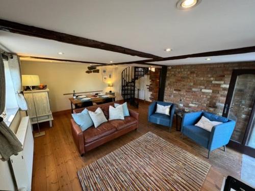 a living room with a couch and two blue chairs at The Quintessential Dorset Cottage in Lytchett Matravers