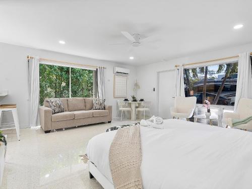 a white bedroom with a large bed and a couch at Beachside Studio in Hollywood