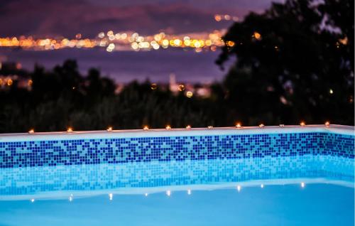 a blue swimming pool with a city in the background at Amazing Home In Kastel Stafilic in Kastel Stafilic