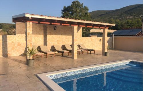 a swimming pool with chairs and a pavilion next to a building at Amazing Home In Kastel Stafilic in Kastel Stafilic