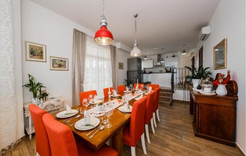 a dining room with a long table and orange chairs at Amazing Home In Kastel Stafilic in Kastel Stafilic