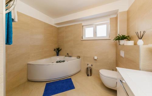 a bathroom with a white tub and a toilet at Amazing Home In Kastel Stafilic in Kastel Stafilic