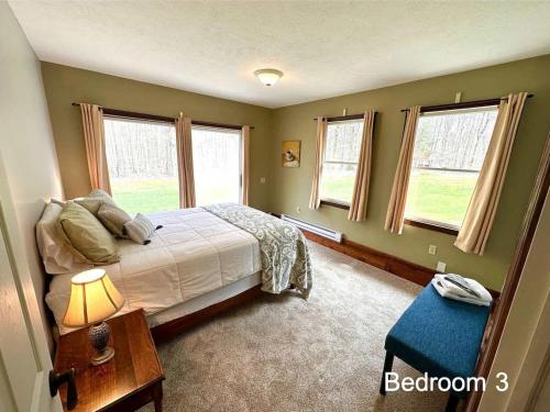 Un dormitorio con una cama y una mesa y ventanas. en 27 Acre Wine Country Estate, en Austinburg