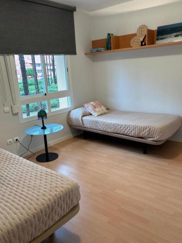 a room with two beds and a table and a window at Charming 3 Bedroom apartment with sea view in the heart of Sotogrande in Sotogrande
