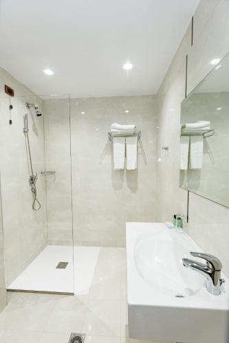 a white bathroom with a sink and a shower at Hotel Fieri in Fier