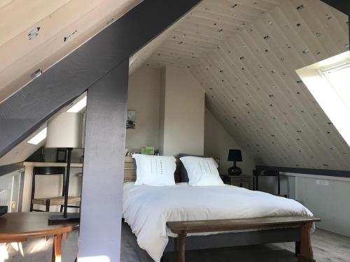 - une chambre avec un lit avec des draps blancs et une table dans l'établissement Seaview espace, calme et confort face a la mer, à Pleubian