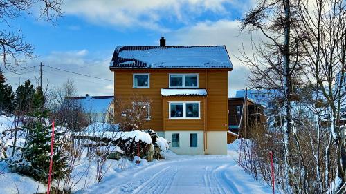 a yellow house with snow on top of it at Nonstinden View Lofoten in Ballstad