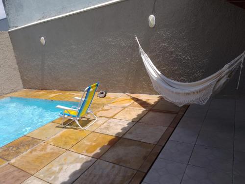 a hammock and a chair in a swimming pool at Melhor Casa de Curitiba pra vc in Curitiba