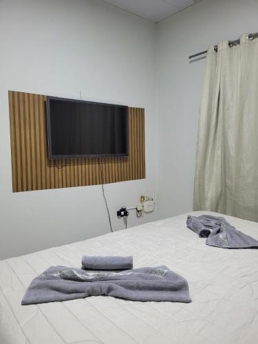 two towels on a bed with a flat screen tv at Casa funcional - 02 quartos, 02 camas de casal, 01 cama de solteiro, cozinha gourmet e garagem para carro pequeno in Ji-Paraná