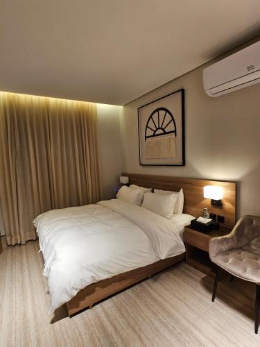 ein Schlafzimmer mit einem großen weißen Bett und einem Stuhl in der Unterkunft سدارا للأجنحه الفندقيه in Riad