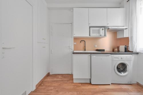 une cuisine blanche avec une machine à laver à l'intérieur dans l'établissement Charming appartment marais, à Paris
