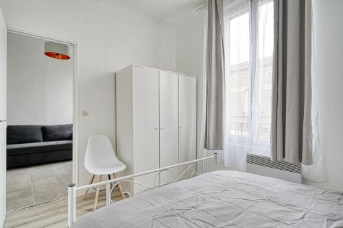 une chambre blanche avec un lit et une chaise dans l'établissement Appartement fonctionnel & lumineux-Portes de Paris, à Argenteuil