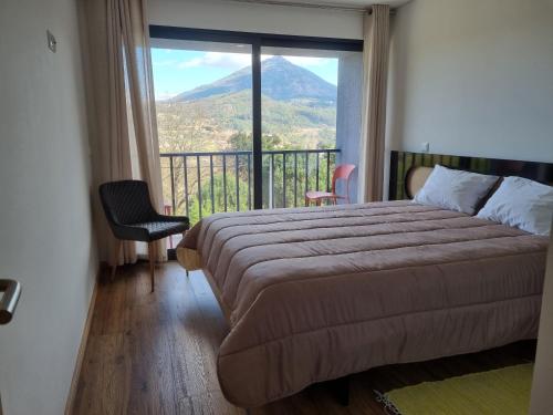 a bedroom with a bed and a view of a mountain at Felicidade in Mondim de Basto