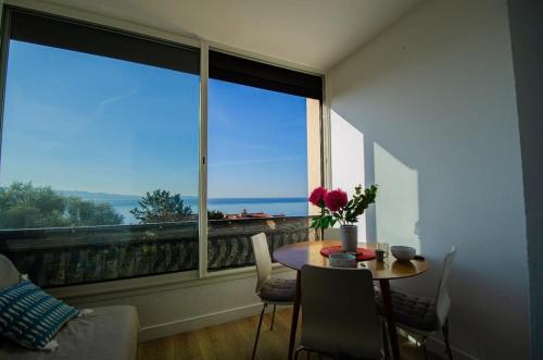 une pièce avec une table et une grande fenêtre dans l'établissement Casamea - Studio Vue Mer, Parking, Plage, Clim, à Ajaccio