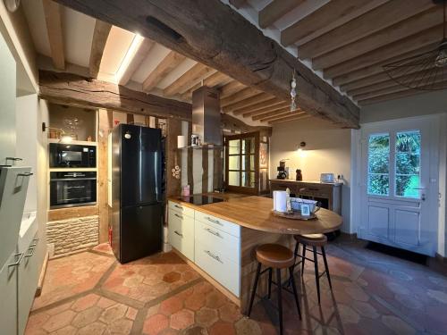 Il comprend une cuisine équipée d'un réfrigérateur noir et d'une table. dans l'établissement Douceur normande, à Thiberville