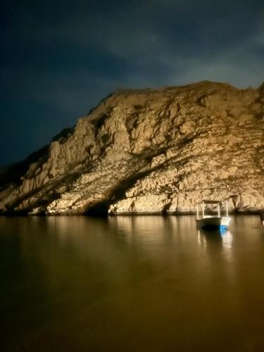a boat in the water in front of a mountain at Camping, Hiking and Dhow Trip- Musandam Uncovered in Dibba