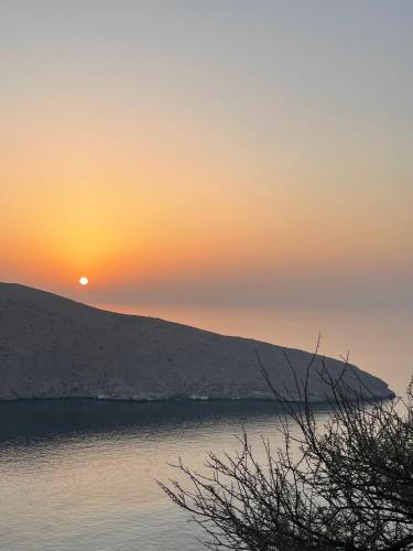 a sunset over a body of water with the sun setting at Camping, Hiking and Dhow Trip- Musandam Uncovered in Dibba