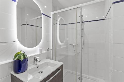 une salle de bain blanche avec un lavabo et une douche dans l'établissement Appartement à Cannes, à Cannes
