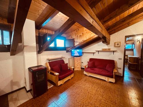 a living room with two red couches and a tv at Rifugio del Sole Apartment in Monclassico