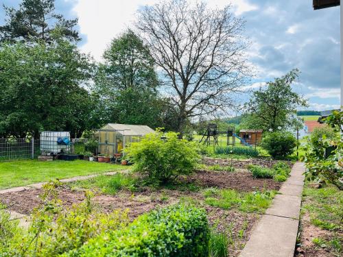 a garden with a greenhouse and a playground at Ferienwohnung Peters (EG) in Hünfeld