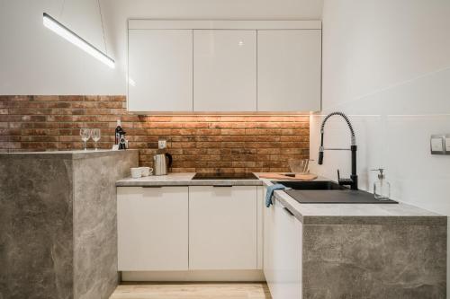 una cocina con armarios blancos y una pared de ladrillo en Rynek 2A - Old Town, en Wroclaw