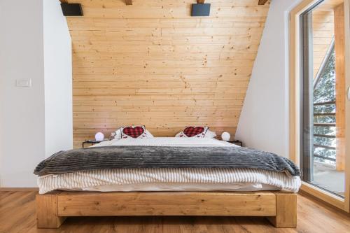 a bedroom with a bed with a wooden wall at Pohorska Gozdna Vila in Pohorje