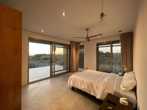 a bedroom with a large bed and large windows at Arroyo Escondido-Luxe Oceanview Contemporary Home with all the Extras in Todos Santos