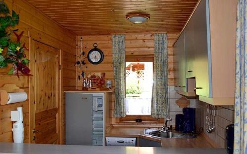 哈瑟尔费尔德Ferienhaus Nr 51, Typ B, Ferienanlage Blauvogel, Hasselfelde, Harz的厨房配有冰箱和墙上的时钟