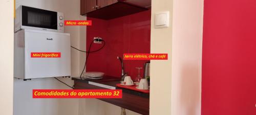 a kitchen with red walls and a tv on a wall at Príncipe de Mónaco Boutique House in Angra do Heroísmo