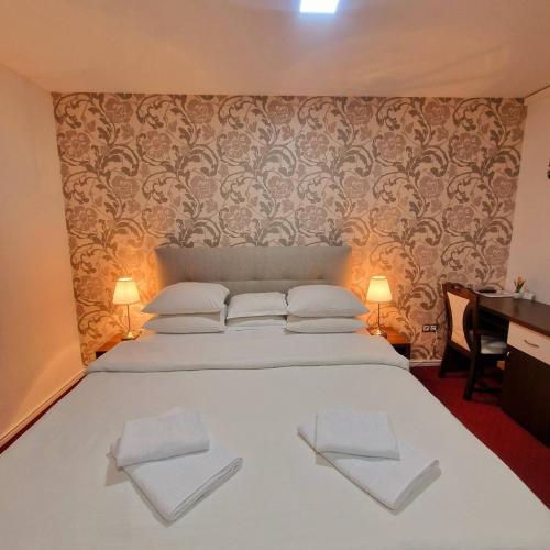 a bedroom with a white bed with two towels on it at Swiss Plus Hotel in Bihać