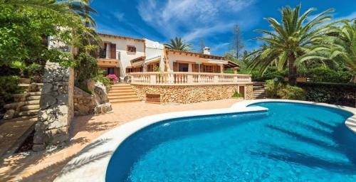 a villa with a swimming pool in front of a house at Schönes Haus mit Pool direkt am Meer in Costa des Pins