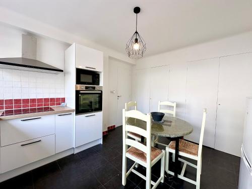 une cuisine avec des armoires blanches et une table et des chaises dans l'établissement 3P refurbished Cannes Palm Beach 200 m from the beaches, à Cannes