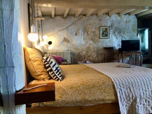 a bedroom with a bed and a television in it at La grotte du pèlerin - Appartement semi-troglodyte in Saintes