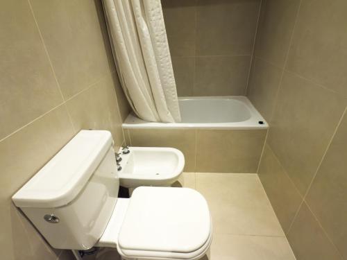 a bathroom with a toilet and a bath tub at Austral Departamentos in Ushuaia