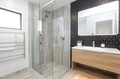 a bathroom with a shower and a sink and a mirror at Inn Sophia in Rotorua