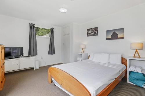 a bedroom with a bed and a flat screen tv at Back of Beyond Cottage in Rotoiti