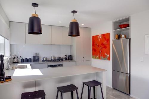 a kitchen with white cabinets and black stools at The Gallery in Rotorua