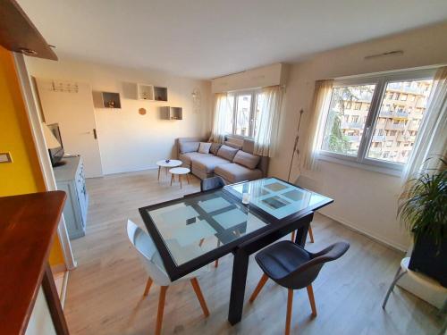 un salon avec une table en verre et des chaises dans l'établissement Appartement spacieux, jacuzzi, lumineux, calme, T2, 56m2, à Boulogne-Billancourt